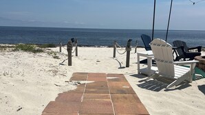 Eine Strandterrasse mit Holztisch, Stühlen und Blick auf das Meer.