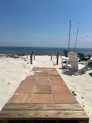 Una terrazza fronte spiaggia con un tavolo di legno, sedie e vista sull'oceano.