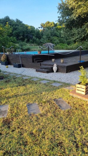 A pool area with a wooden deck, steps leading to the pool, and potted plants. - Ancient millstone of Etna (Pedara)