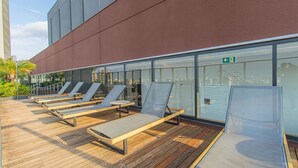 A rooftop lounge area with wooden flooring and metal-framed sun loungers. - Cozy Near Allianz Parque Sp-p1702b (São Paulo)