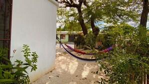 A courtyard with a hammock, a tree, and a building with a balcony. - Casa Todah B&B (Liberia)