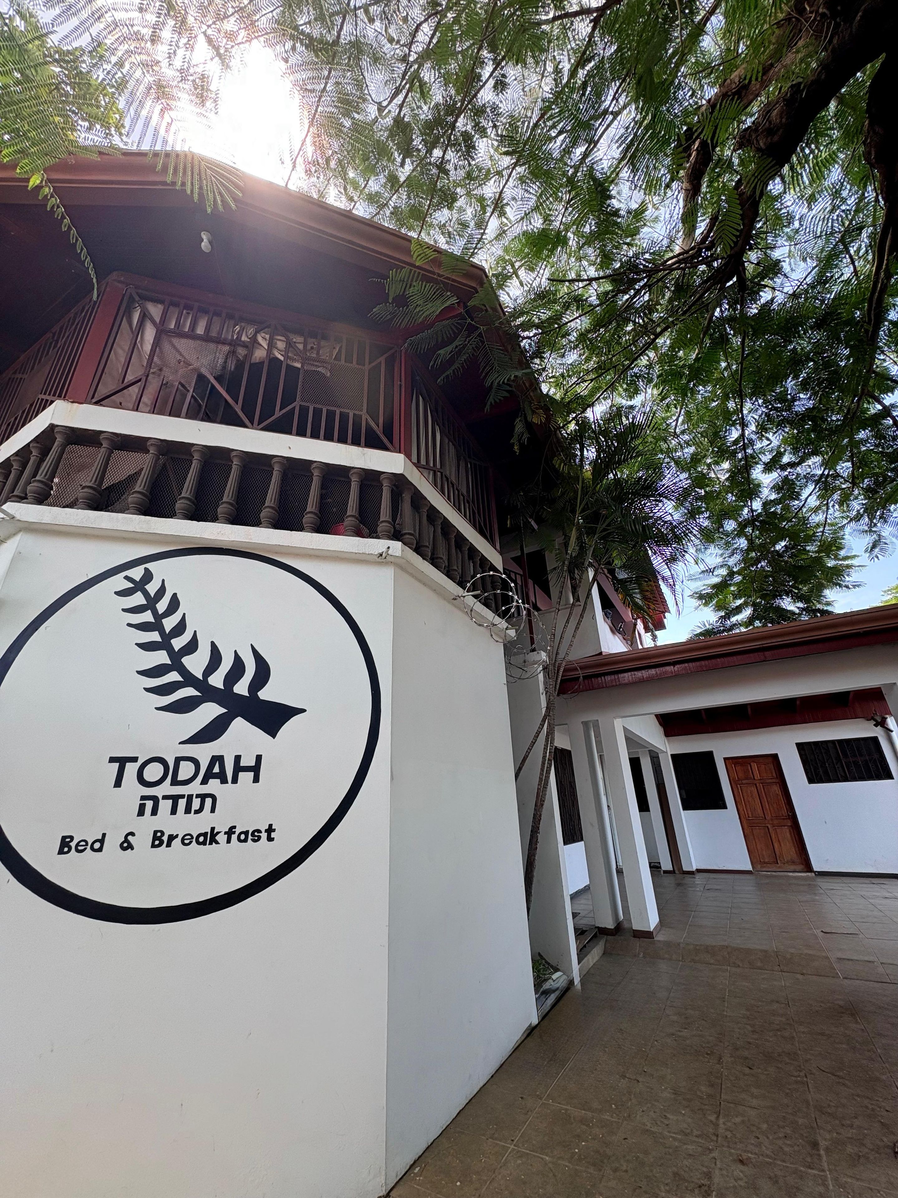 A building with a sign for 'TODAH' and a balcony with a railing.