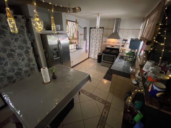 A kitchen with a refrigerator, stove, and various kitchen items.
