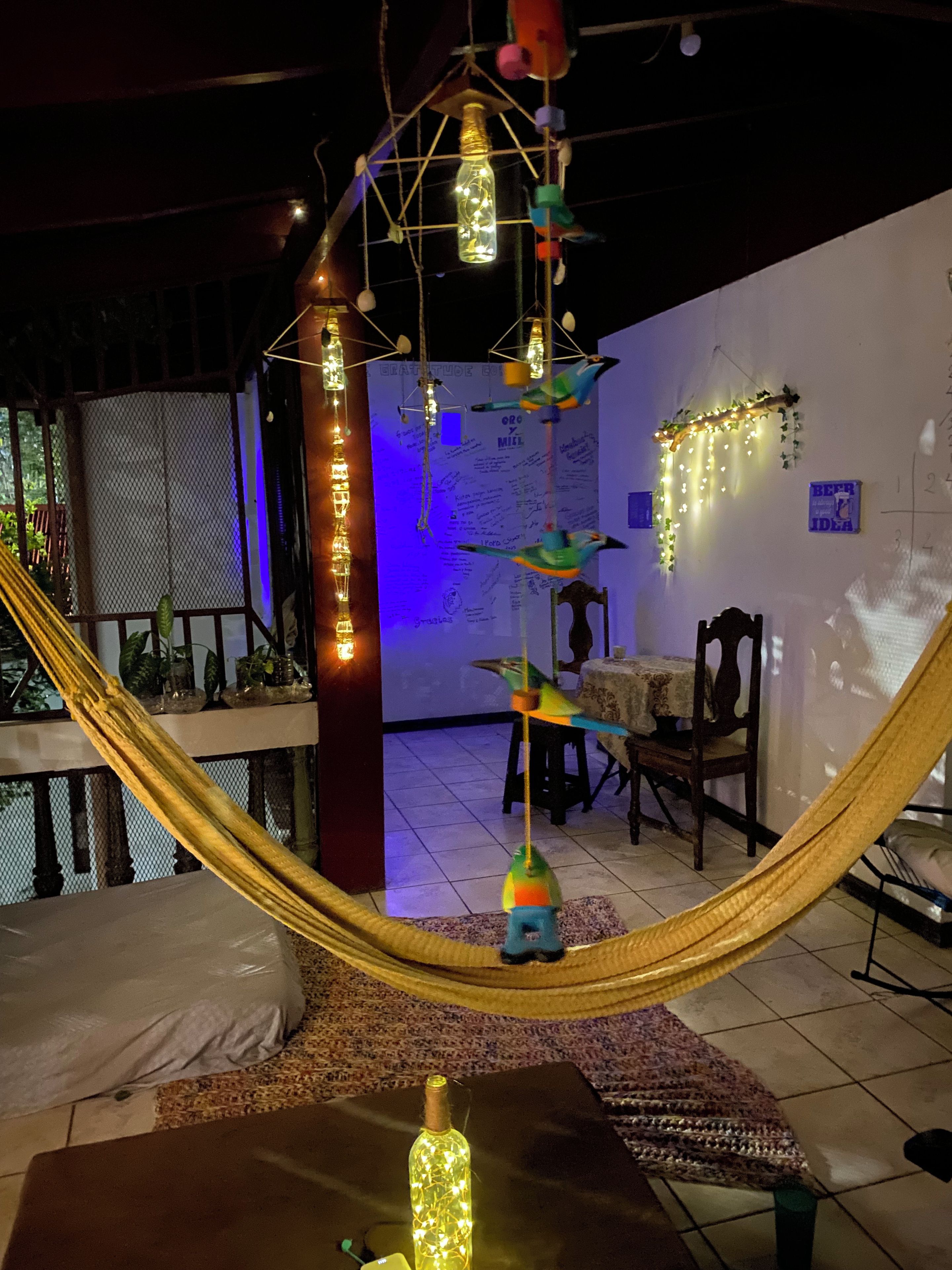 A room with a hammock, hanging light fixtures, and a table with chairs.