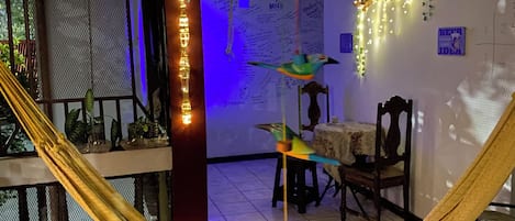 A room with a hammock, hanging light fixtures, and a table with chairs.