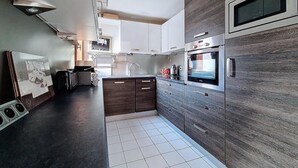 Une cuisine moderne avec des meubles de couleur bois foncé, un évier en acier inoxydable et un four encastré.