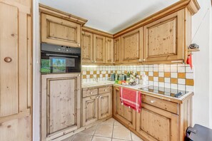 A kitchen with wooden cabinets, a stove, and a tiled backsplash.