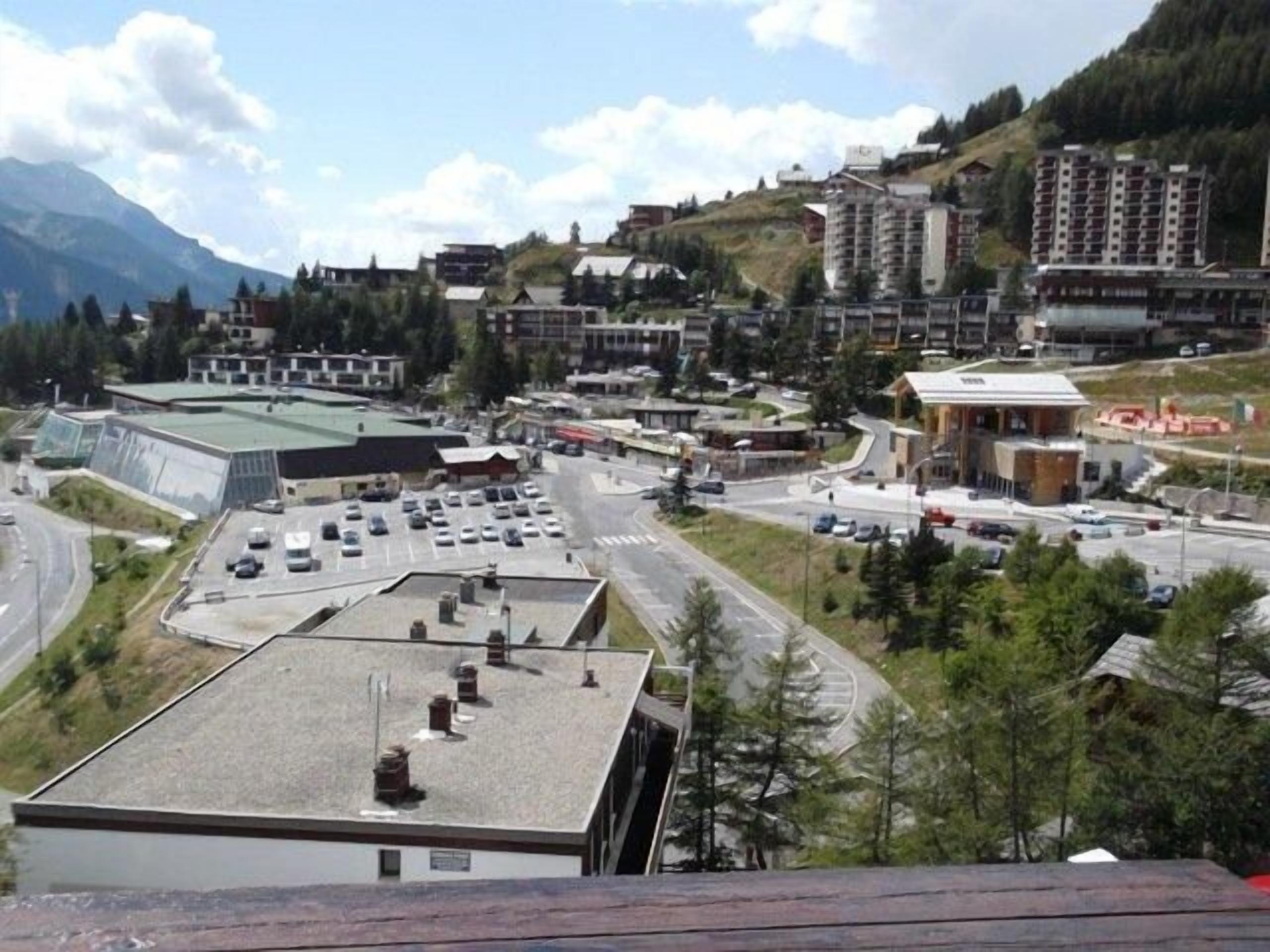 Un pueblo con un estacionamiento, edificios y una montaña al fondo.
