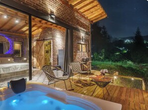 A cozy outdoor area with a hot tub, wooden deck, and seating.