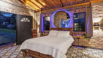 A bedroom with a wooden bed, a brick wall, and a large window.