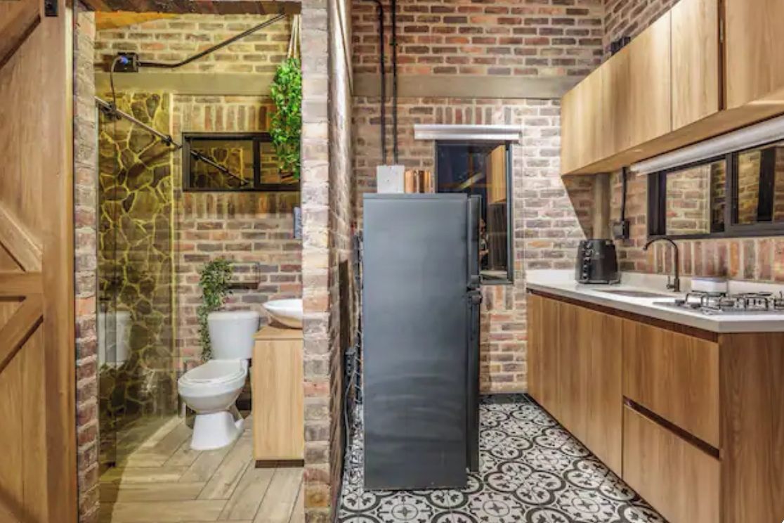 A compact kitchen with a refrigerator, sink, and wooden cabinets.