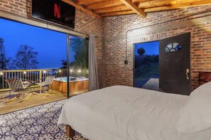 A bedroom with a large bed, a sliding glass door leading to a balcony, and a Netflix sign above the door.