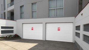 Ein modernes Gebäude mit zwei Garagentoren, jedes gekennzeichnet mit einem roten Notausgangsschild.