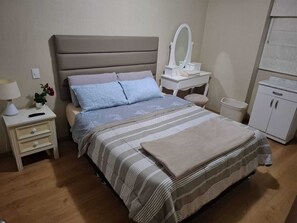 A neatly arranged bedroom with a bed, bedside tables, a vanity with a mirror, a small cabinet, and a lamp. - View of the Magic Circuit and National Stadium. Safe and quiet. 24-hour check-in (Lima)