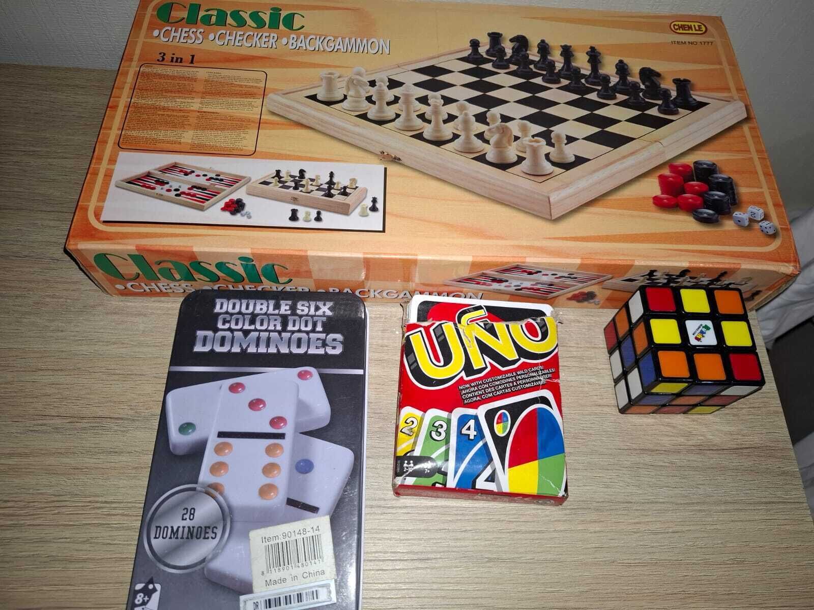Un juego de ajedrez, dominó y un cubo de Rubik sobre una mesa.