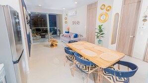 A modern kitchen with a dining area, a sofa, and a view of the city at night.