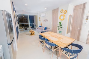 A modern kitchen with a dining area, a sofa, and a view of the city at night.