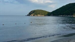 A calm sea with a small island and a beach.