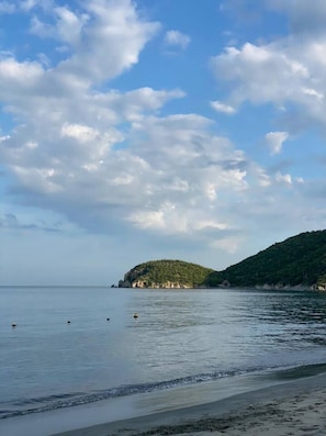 A calm sea with a small island and a beach.
