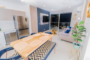 Una cucina moderna con elettrodomestici in acciaio inossidabile, un'area pranzo con tappeti decorati, un divano con cuscini e un'ampia finestra.