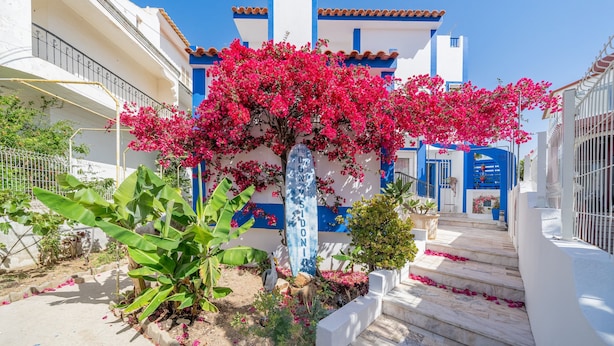A building with a blue and white facade, a white door, and a blue sign with the name 'SIDONIO'.