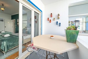 A modern hotel room with a sliding glass door, a round table, a green plant, and a wall with decorative shoes.