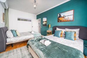 A bedroom with two beds, a nightstand, a lamp, and wall art.