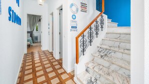 A hallway with a checkered floor, a staircase with marble steps, and a blue wall with a welcome sign.