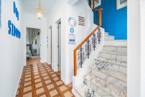 A hallway with a checkered floor, a staircase with marble steps, and a blue wall with a welcome sign.