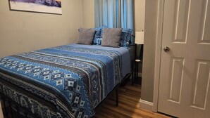 Un dormitorio con cama, ventilador de techo, una puerta y un cuadro en la pared.