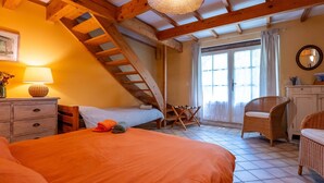 A bedroom with a bed, a dresser, a chair, a lamp, and a staircase. - Bed and Breakfast 'Chambre' with Private Terrace, Shared Garden and Wi-Fi (Saint-Étienne-les-Orgues)