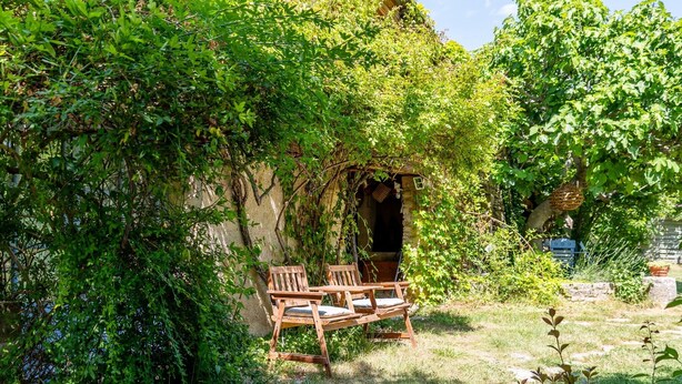 A garden with a wooden bench and a stone wall.