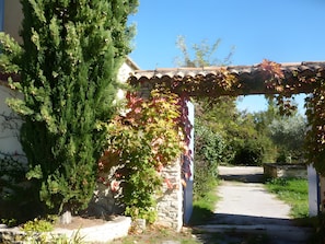 A stone building with a tiled roof, a stone wall, and a pathway leading to a gate.