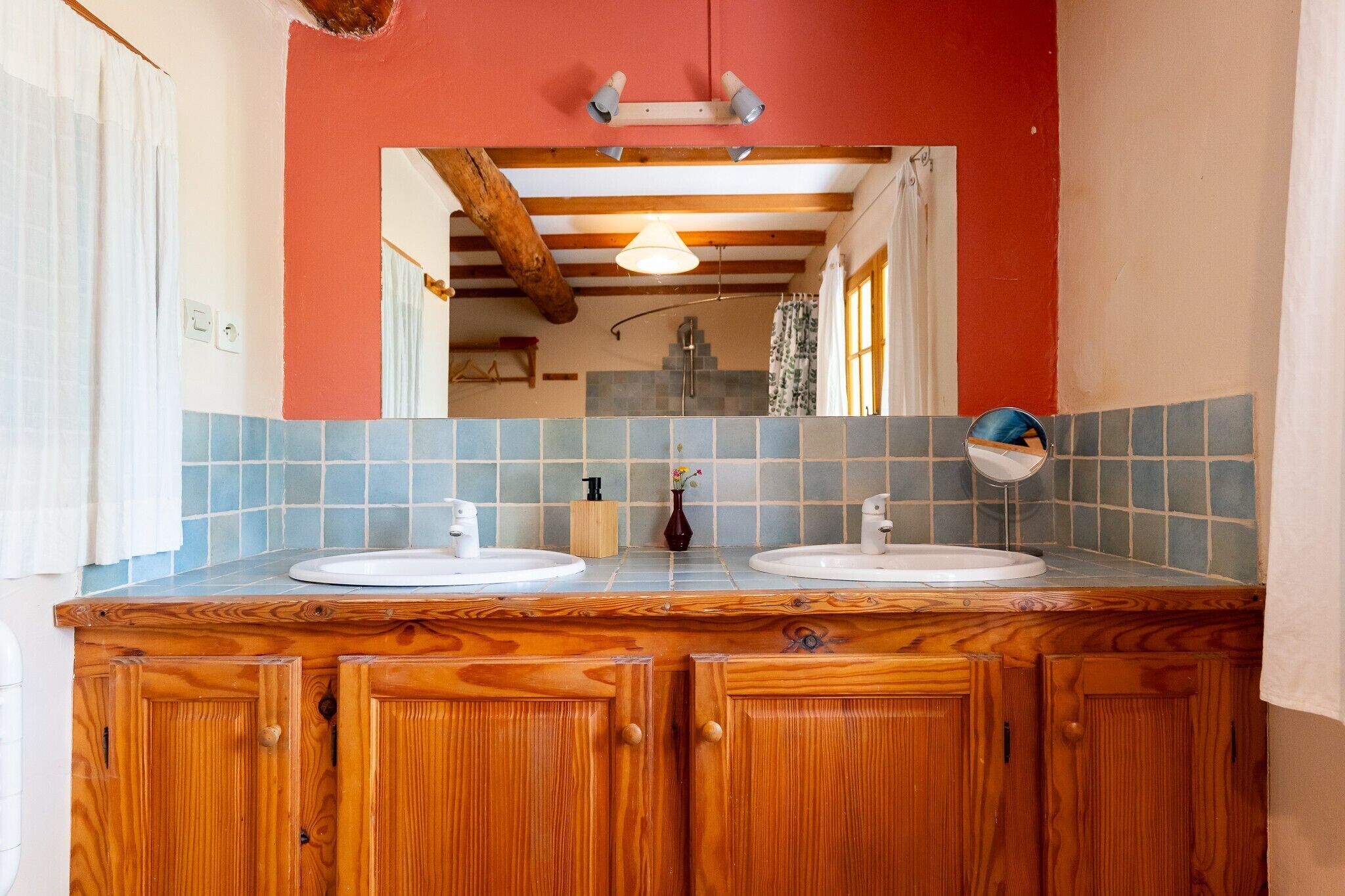 Une salle de bain avec deux lavabos, des meubles en bois, un miroir et une douche visible au fond.