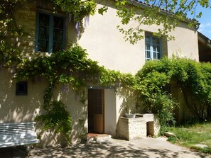A building with a stone facade, a wooden bench, and a door leading to an interior space. - Bed and Breakfast 'Chambre' with Shared Terrace, Shared Garden and Wi-Fi (Saint-Étienne-les-Orgues)