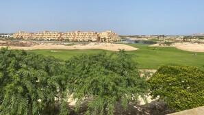 A resort with multiple-story buildings, a golf course, and surrounding greenery.