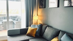 A modern living room with a grey sectional sofa, a floor lamp, and artwork on the wall.