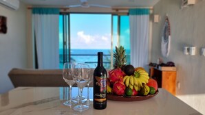 Une table avec une bouteille de vin, des verres et un panier de fruits.