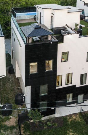A modern multi-story building with a rooftop pool, a black and white facade, and multiple windows. - New Luxe Townhome - Rooftop Pool (Nashville)