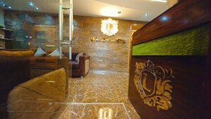 A lobby with a stone wall, a reception desk with a logo, and a sofa. - Nile View (Cairo)
