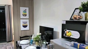 Una cocina moderna con zona de comedor, que incluye una mesa preparada para dos personas, un refrigerador y un televisor.