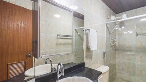 Un baño con puerta de madera, un lavabo con espejo, una ducha con puerta de cristal y un perchero para toallas.