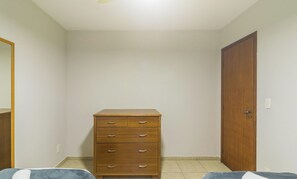 A room with a wooden dresser, a door, and a tiled floor. - Casa 4Q em Condomínio c\/ Piscina NAT0202 (Cabo Frio)