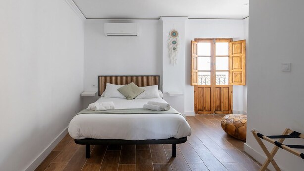 Quarto com cama, porta de madeira e janela.