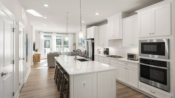 A modern kitchen with white cabinetry, stainless steel appliances, and a central island.