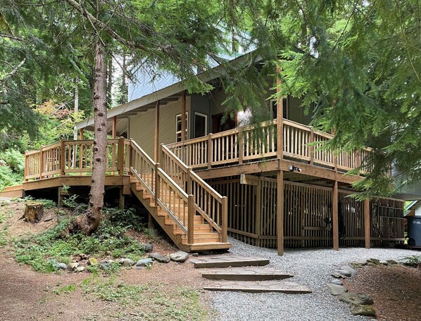 A two-story wooden cabin with a deck and stairs leading to the entrance.