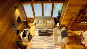 A cozy wooden cabin interior with a sofa, a coffee table, and a fireplace.