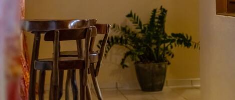 A dining area with a wooden table and chairs, a potted plant, and a wall-mounted light fixture.