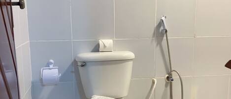 A bathroom with a toilet, a shower, and a trash bin.