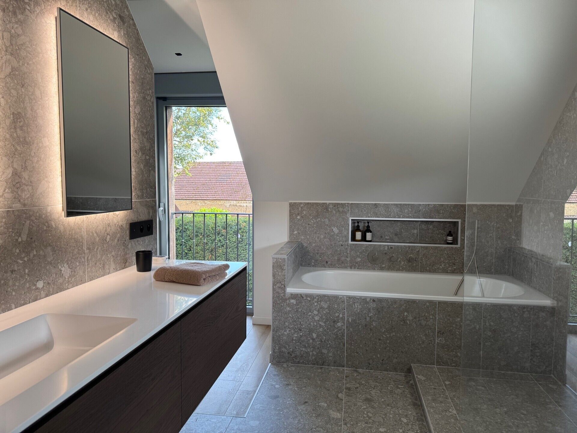 Une salle de bain moderne avec une grande baignoire, un meuble-lavabo avec un miroir et une étagère contenant des articles de toilette.